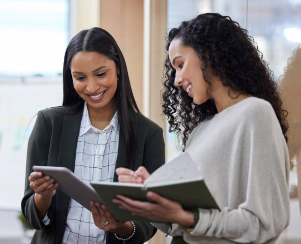 istock Shot of two businesswomen working together while using a digital tablet 1365606066
