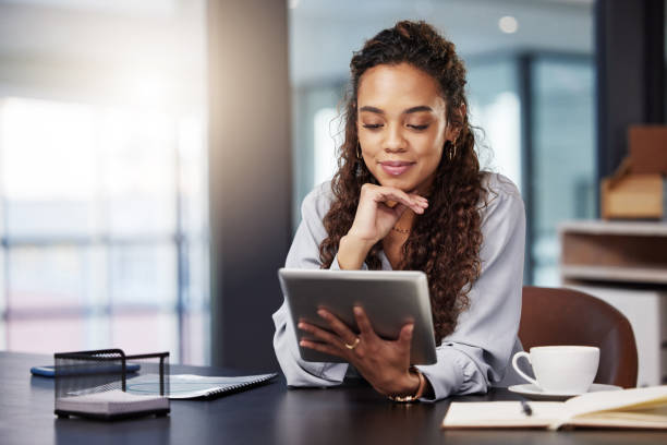 Shot of a young businesswoman using a digital tablet while at work Ready to read on the go using digital tablet stock pictures, royalty-free photos & images