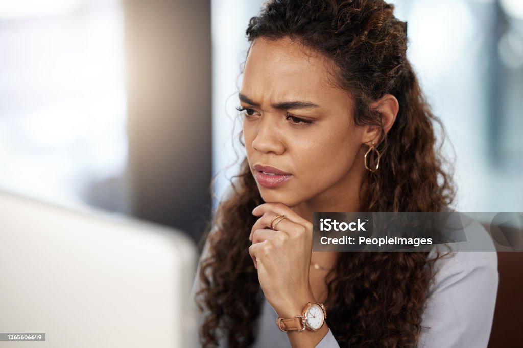Shot of a young businesswoman looking confused while working on her computer This might need a closer look Uncertainty Stock Photo