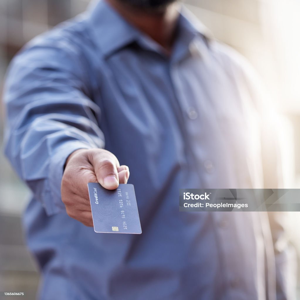 Shot of a unrecognizable man holding a credit card outside Pay up Credit Card Stock Photo