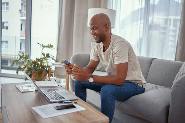 istock Shot of a young man using a laptop and credit card while working from home 1365606833