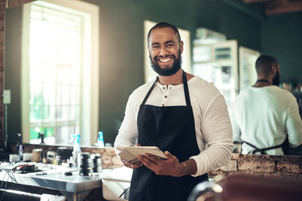 istock Shot of a handsome young barber standing alone and using a digital tablet in his salon 1365608050