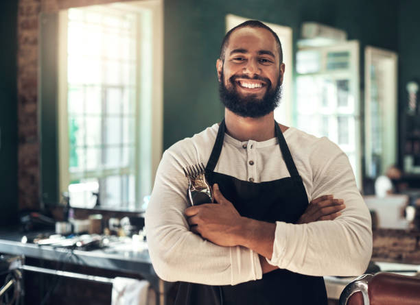 istock Shot of a handsome young barber standing with his arms folded while holding a shaving machine in his salon 1365608052