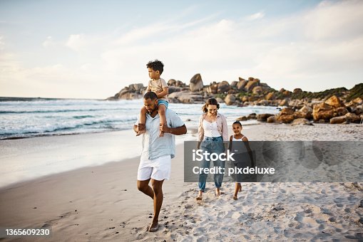 istock Shot of a young couple and their two kids spending the day at the beach 1365609230