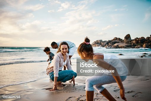 istock Shot of a young couple and their two kids spending the day at the beach 1365609755
