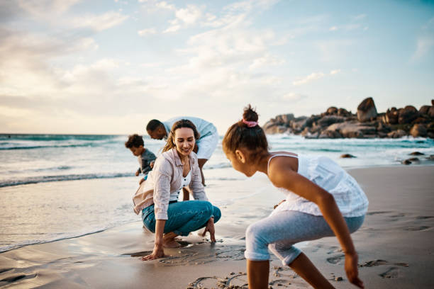 zdjęcie młodej pary i dwójki ich dzieci spędzających dzień na plaży - summer idyllic carefree expressing positivity zdjęcia i obrazy z banku zdjęć