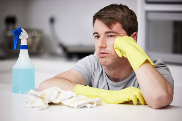 istock Shot of a young man looking bored while cleaning the kitchen at home 1365610644