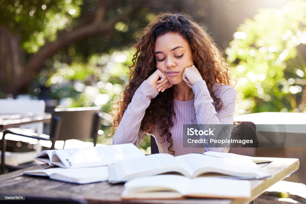 Shot of a young female student studying at a cafe All this studying but where's the motivation? Boredom Stock Photo