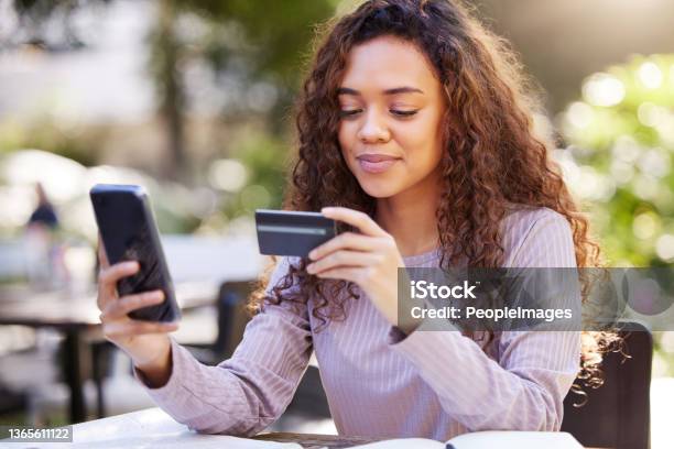 Shot Of A Young Woman Using A Credit Card And Phone At A Cafe Stock Photo - Download Image Now