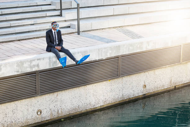 foto de un hombre de negocios sentado al borde de un cuerpo de agua con equipo de buceo - swimming pool water people sitting fotografías e imágenes de stock