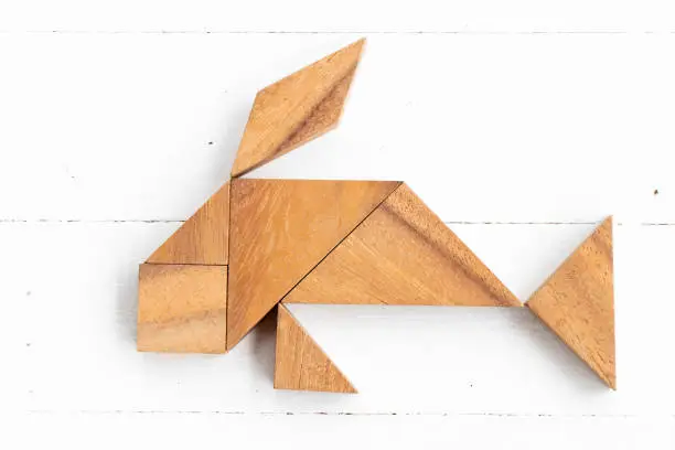 Photo of Wood tangram puzzle in fish or carp shape on white wood background