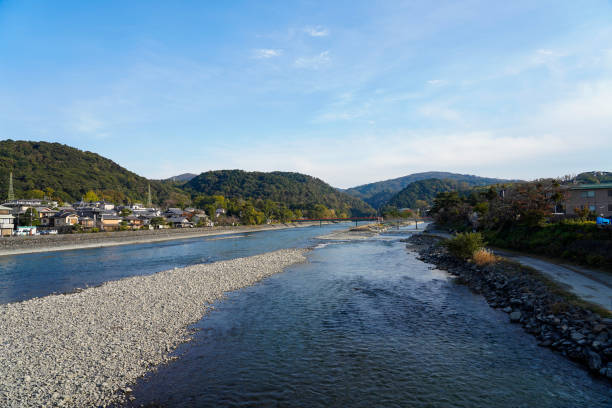 가을철에 아라시야마강을 따라 멀리 떨어진 카츠라강을 건너는 관광객을 볼 수 있습니다. - cross autumn sky beauty in nature 뉴스 사진 이미지