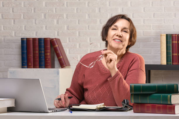 Senior woman looking at camera during break in working process stock photo