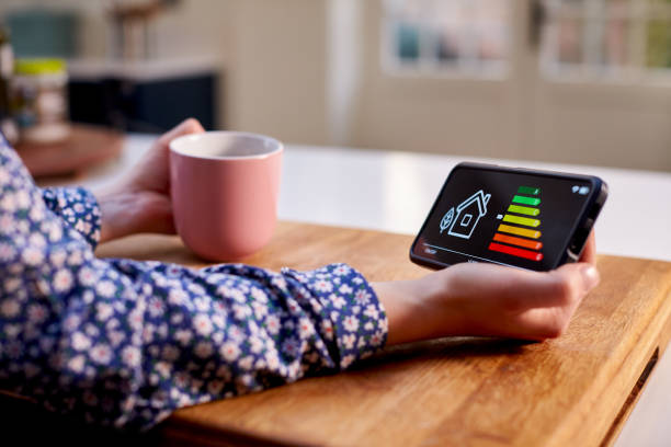 gros plan d’une femme tenant un compteur d’énergie intelligent dans une cuisine mesurant l’efficacité énergétique - intérieur de maison photos et images de collection