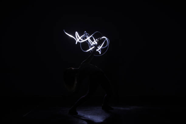 istock Modern art dancer, dancing in front of a black background with neon blue light while stretching and twisting her body. 1365616016