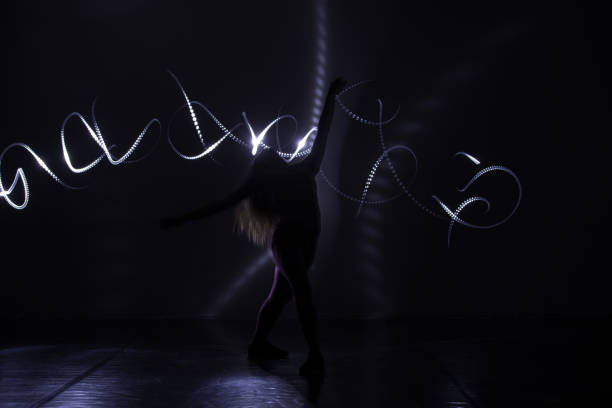 istock Modern art dancer, dancing in front of a black background with neon blue light while stretching and twisting her body. 1365616026