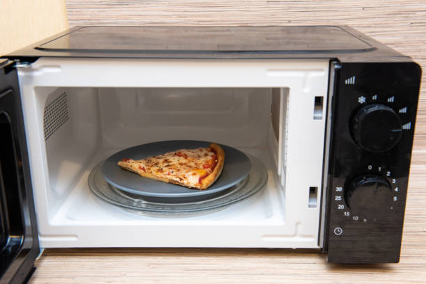 istock Plate with slice of pizza in microwave oven 1365616064