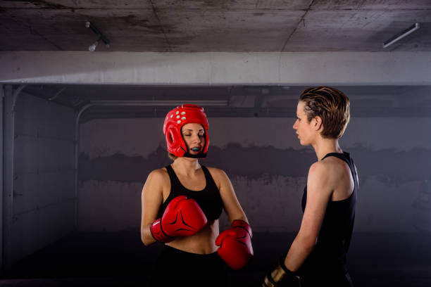 istock Two female boxers putting on boxing gloves before their fight inside a garage 1365617478