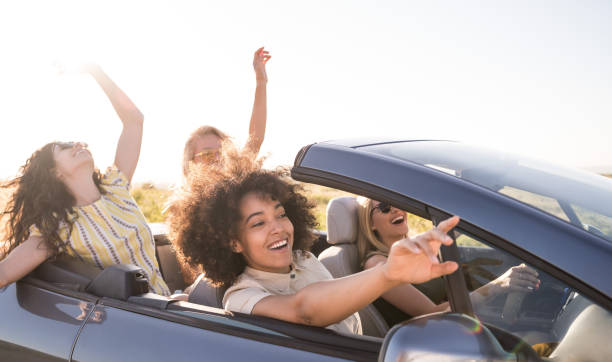 istock Girlfriends having fun on road trip with car 1365621302