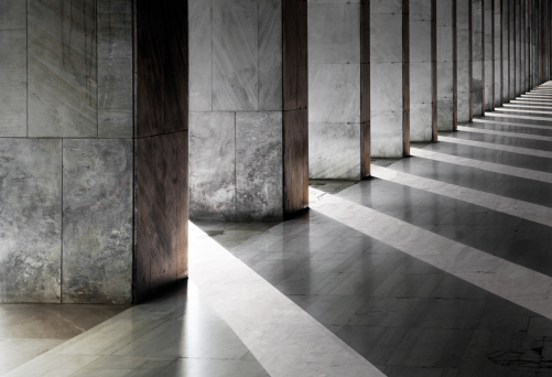 Row of columns with sunlight in the gaps and reflected in shiny floor