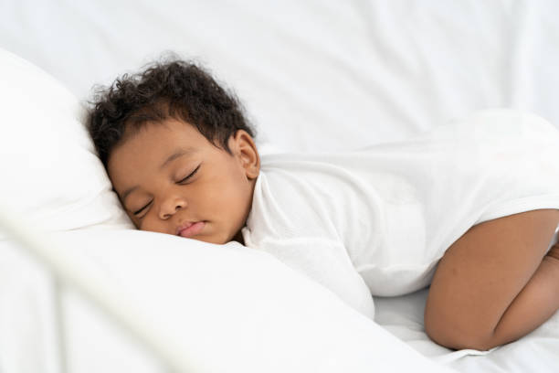 istock black african american baby sleeping on a white mattress. 1365626350
