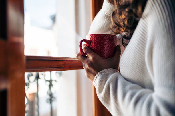 istock Unrecognizable woman drinking coffee by the window 1365626725