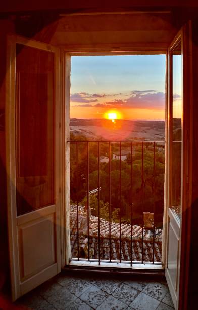 a golden tuscan sunset as seen through an open 3rd floor balcony doorway exploring historic montelcino, tuscany, italy - september 2021 golden hour wine stock pictures, royalty-free photos & images