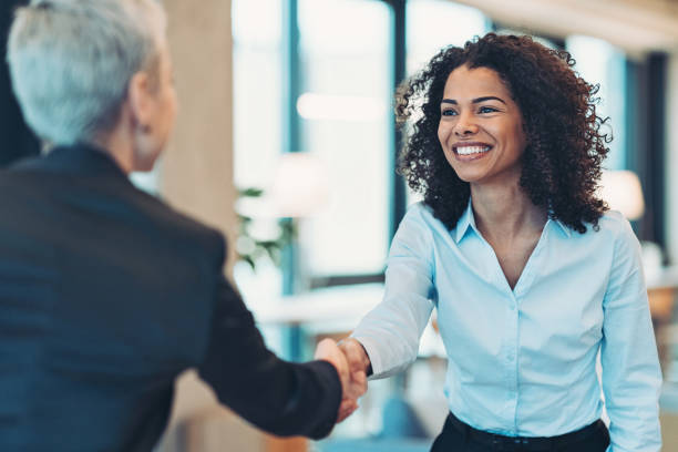donna d'affari sorridente che saluta un collega in una riunione - handshake foto e immagini stock