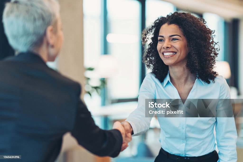 Smiling businesswoman greeting a colleague on a meeting Businesswomen shaking hands in the office Handshake Stock Photo
