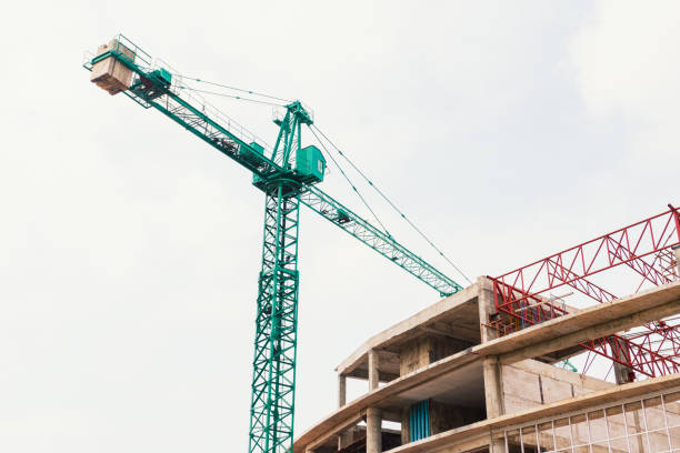 istock Construction crane with clouds sky background at construction site. tower crane with blue sky Green lifting crane on a cloudy blue sky background. A Look Up of The Tower Crane. 1365638656