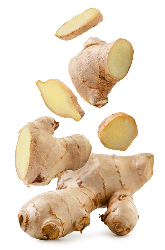 Pieces of ginger are falling on a white background. Isolated