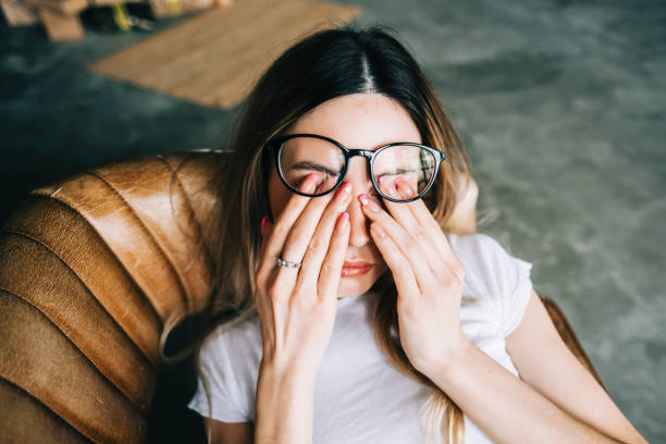 la giovane donna si strofina gli occhi dopo aver usato gli occhiali. concetto di dolore oculare o affaticamento. - rubbing foto e immagini stock