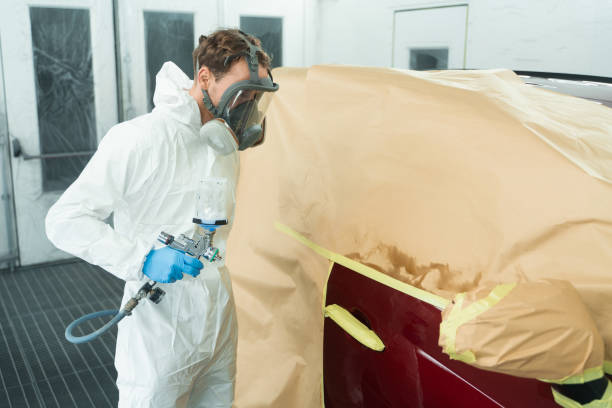 istock Auto painter with spray gun in car painting booth 1365643566