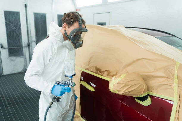istock Auto painter with spray gun in car painting booth 1365643593