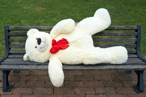istock big polar plush bear with red tie, lying on the a bench 1365646959