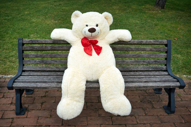 istock big polar plush bear with red tie, sits on a bench 1365646967