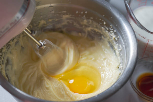 elaboración de un pastel: añadir un huevo y batir la masa. - batidora eléctrica fotografías e imágenes de stock