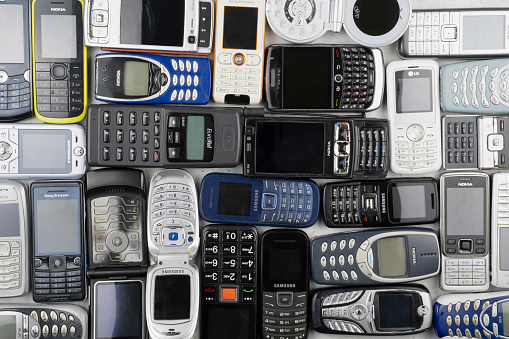 Prague, CZ -  12 December 2021:  A lot of old used mobile phones with keyboards, Various brands. Many types and generations of mobile smartphone gadgets are in heap. Editorial