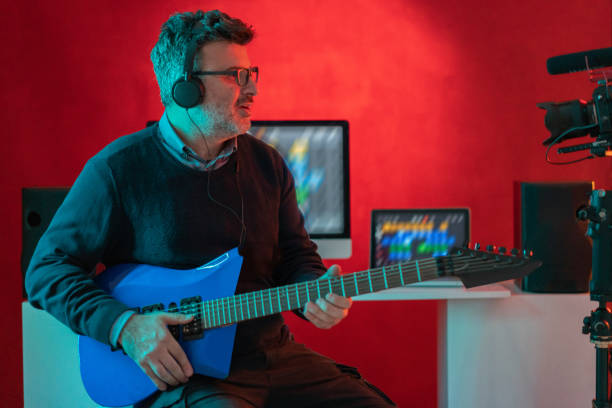istock Camera shooting a musician man playing the guitar in neon record studio. 1365649415