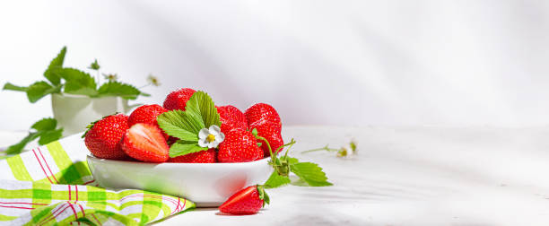istock Fresh strawberries in a bowl on white stone table, banner 1365649437