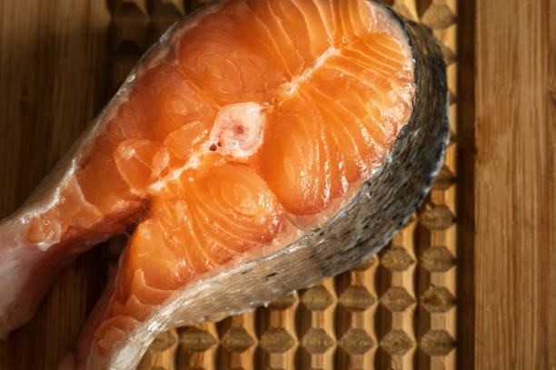 raw salmon filet on wooden cutting board