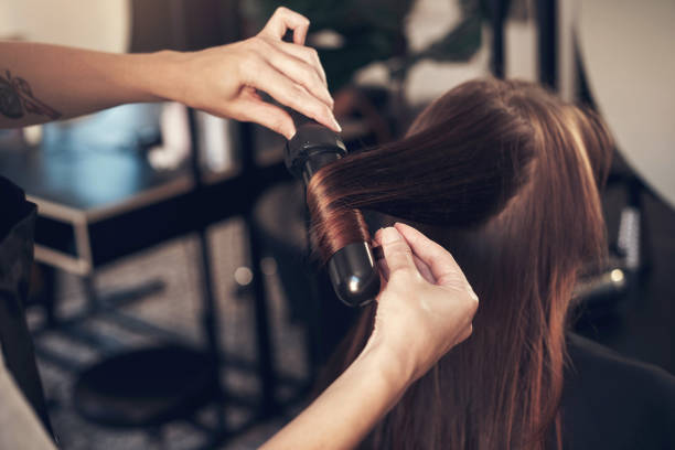 Shot of a hairstylist using a curling iron to do her client's hair Going for that bouncy and flawless look curling tongs photos stock pictures, royalty-free photos & images