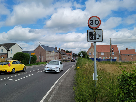 A row of terraced houses newly built but in traditional style in Blandford Forum, Dorset, England, UK. There is a speed camera on this section of road and a speed limit sign in the foreground.