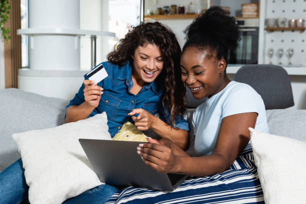 Two young happy women online buying a ticket for vacation and booking the hotel in touristic resort for holidays on laptop. Two female friends online shopping with credit card from their apartment. dos jóvenes mujeres felices en línea comprando un boleto para vacaciones y reservando el hotel en el complejo turístico para vacaciones en una computadora portátil. dos amigas comprando en línea con tarjeta de crédito desde su apartamento.