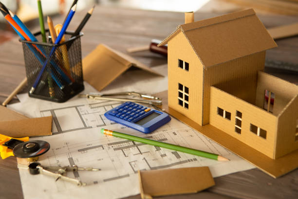 istock Workplace of architect - construction drawings, scale model and tools. Modern house design, real estate concept. 1365657508