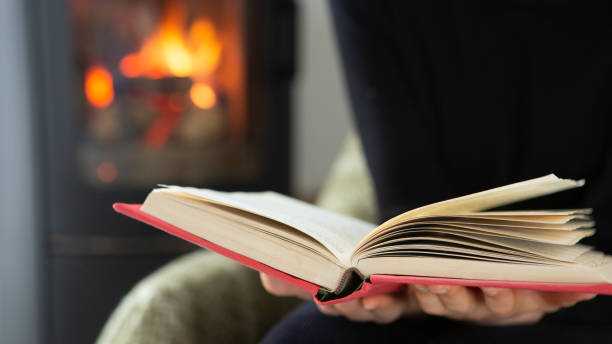 istock Female reading a book by the fireplace. Cozy winter lifestyle 1365657601