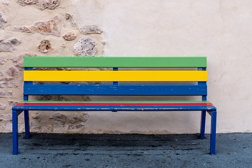Colorfully painted wooden bench, with a wall in the background.