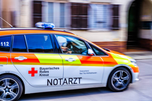 Injured man on patient transport stretcher. Ambulance staff member assisting injured person with transport stretcher. Paramedics assisting injured person first aid on road