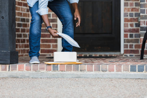 Unrecognizable man picks up packages on doorstep An unrecognizable man bends over to pick up packages that were left on his front porch by a delivery driver. front stoop photos stock pictures, royalty-free photos & images