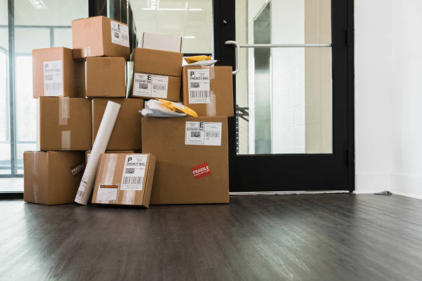 Large stack of delivered packages in office A large stack of cardboard boxes, envelopes and a cylinder are sitting inside a door of an office. parcel stock pictures, royalty-free photos & images